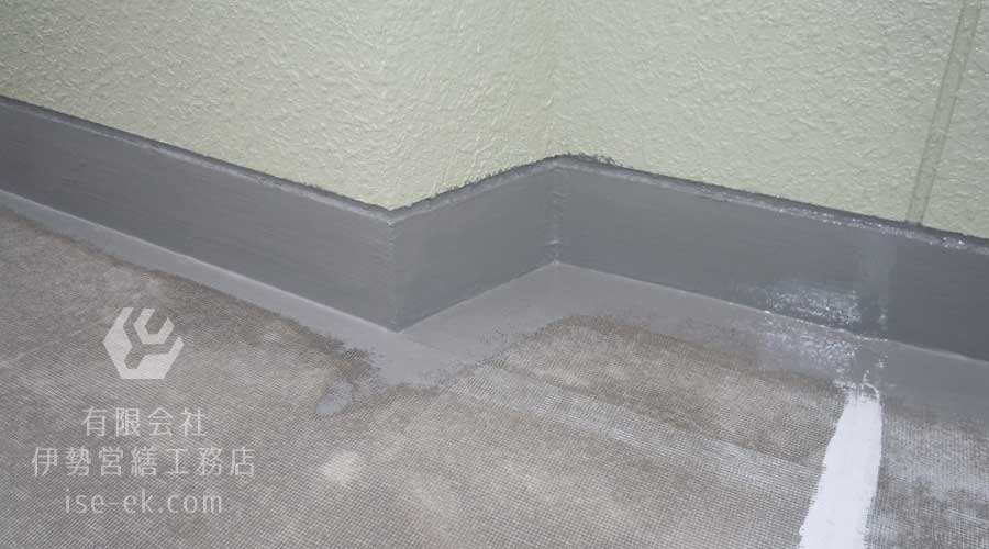 屋上防水層にトップコートを塗布する作業の様子