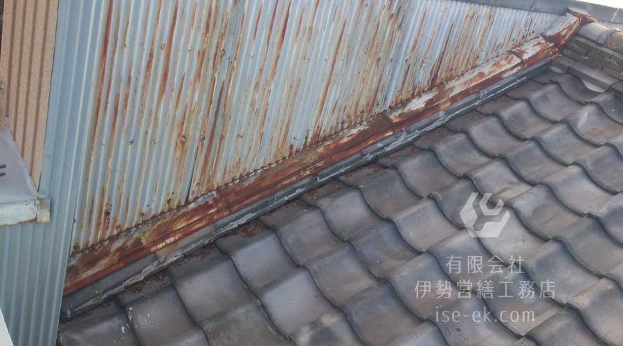 酷く錆びついた瓦屋根に設置された古い水切りトタン